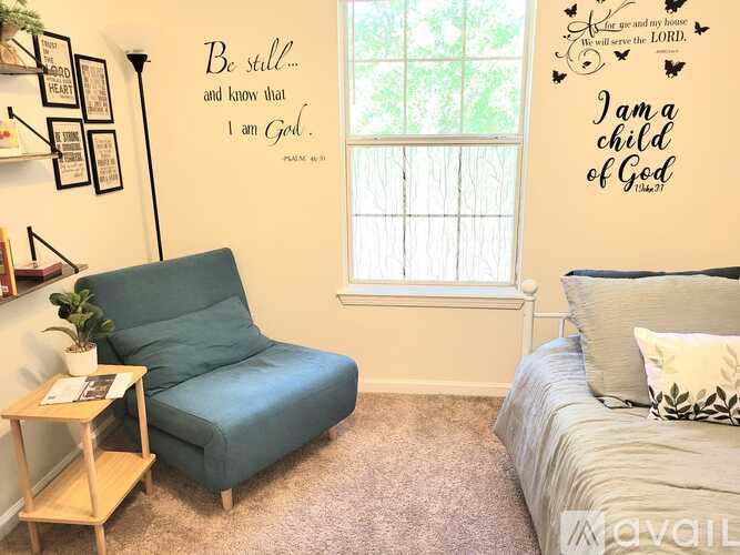 A bedroom with a bed, chair, and wall decorations with Bible verses.