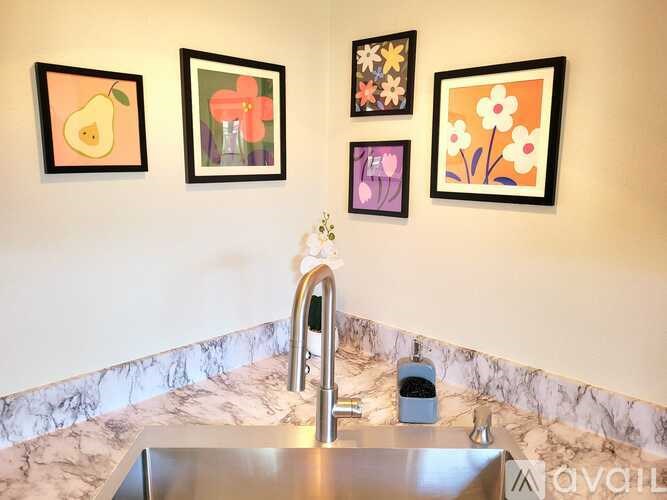 A bathroom with a sink and four pictures on the wall.