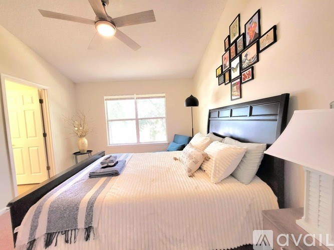 A bedroom with a bed, pillows, a ceiling fan, and a window.