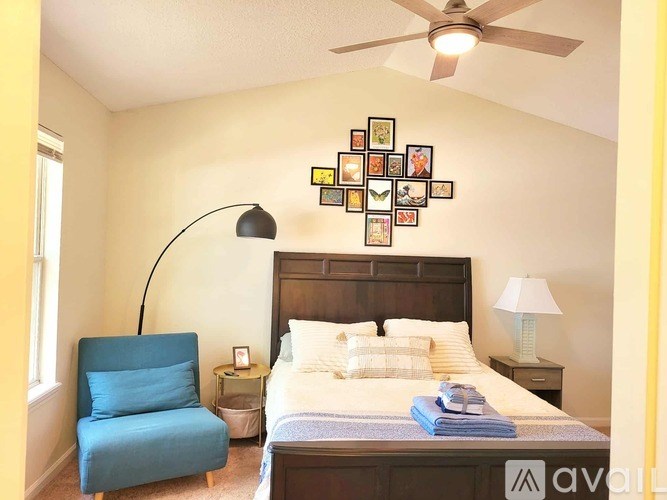A bedroom with a bed, a chair, and a ceiling fan.
