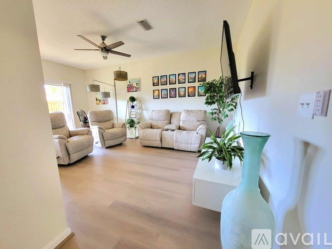 A living room with a white sofa, a white coffee table, and a green vase.
