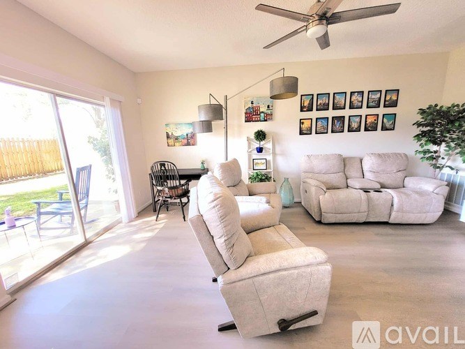 A living room with a white couch and a fan on the ceiling.