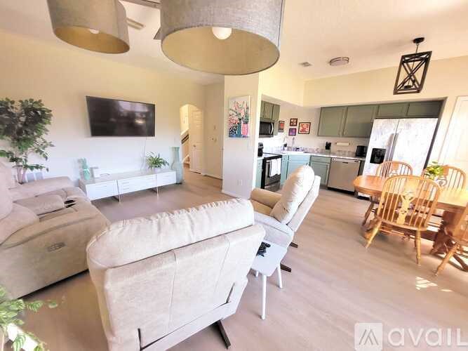 A living room with a white couch and a television mounted on the wall.