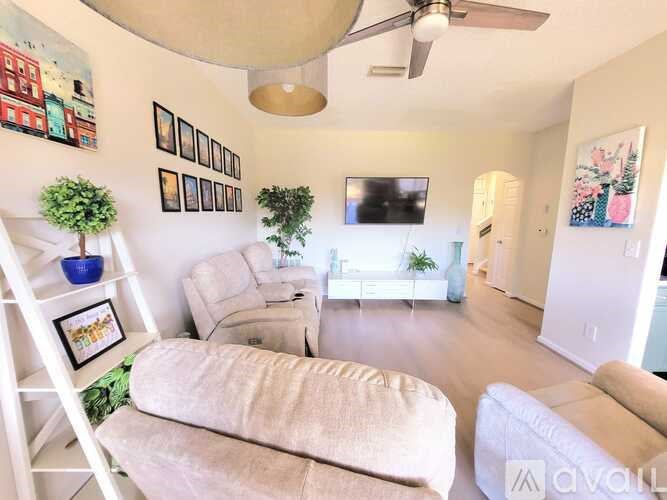 A living room with a white couch, a white chair, a white shelf, a white wall, a white ceiling, a white floor, a white table, a white television, a white couch, a white chair, a white