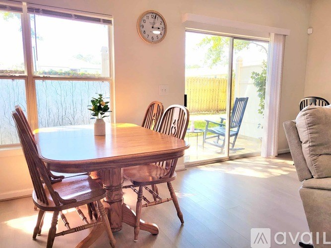A dining room with a table and chairs and a clock on the wall.