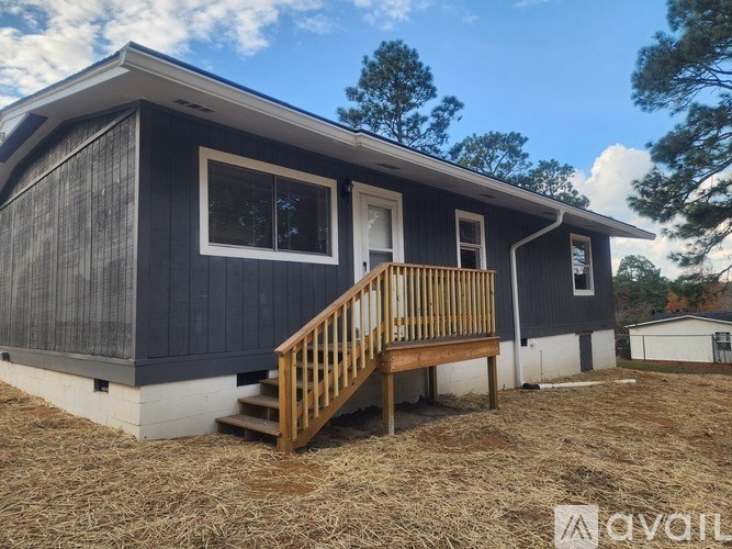 A black and white mobile home with a porch and a brown railing.
