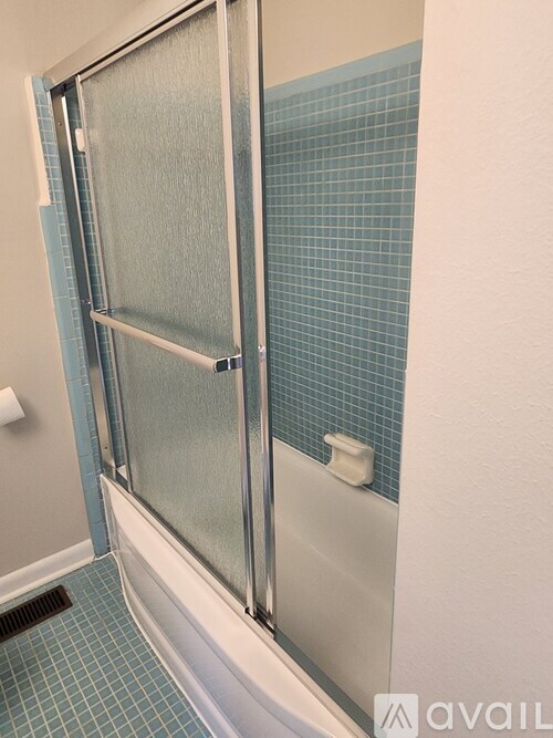 A shower with a glass door and a white base.