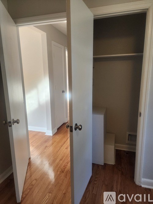A hallway with three doors and a shelf.