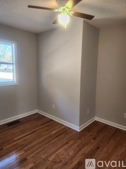 A room with a ceiling fan and wooden flooring.