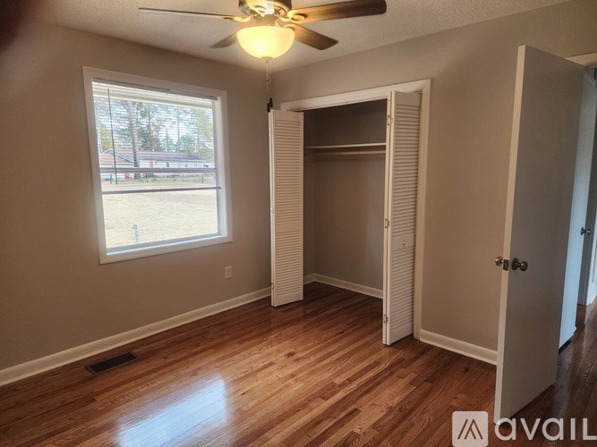 A room with a ceiling fan and a large window.
