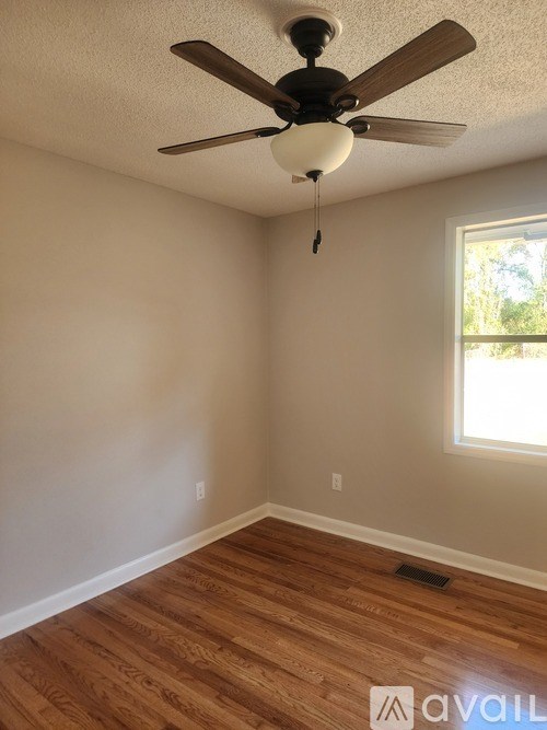 A room with a ceiling fan and wooden flooring.