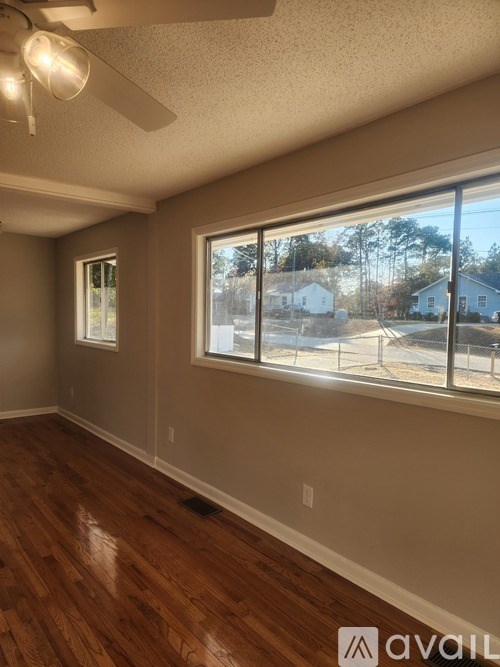 A room with a ceiling fan and a window overlooking a street.