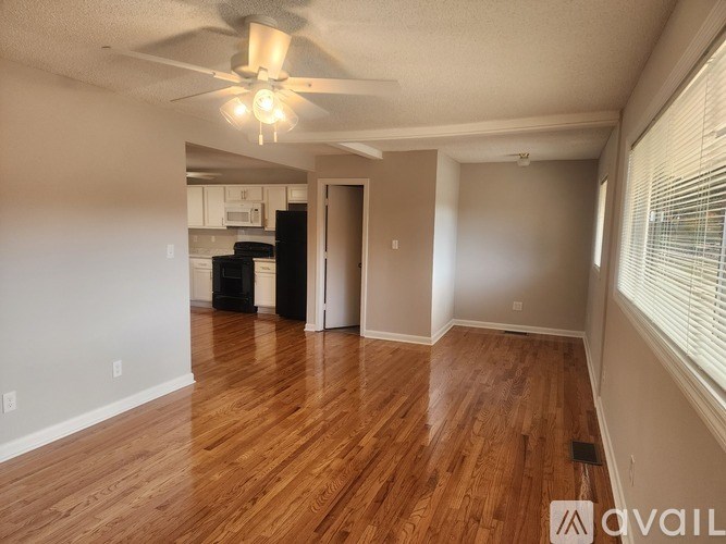 A room with wooden flooring and a doorway leading to another room.