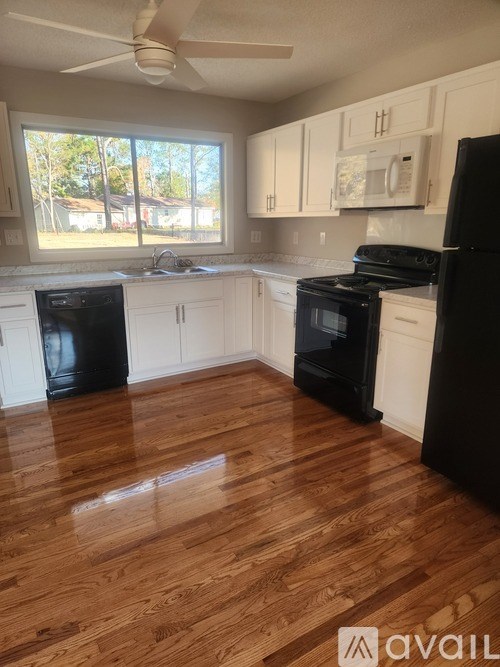 A kitchen with black appliances and white cabinets.