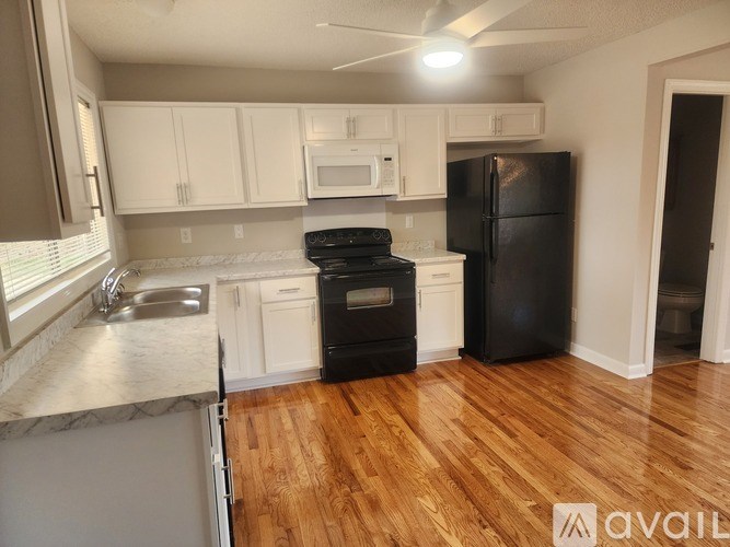 A kitchen with a white door and a wooden floor.