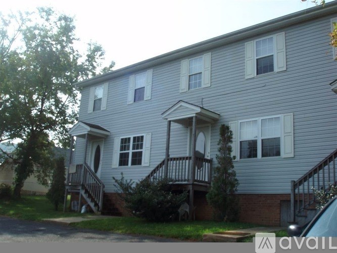 A grey two-story house with a balcony on the second floor.