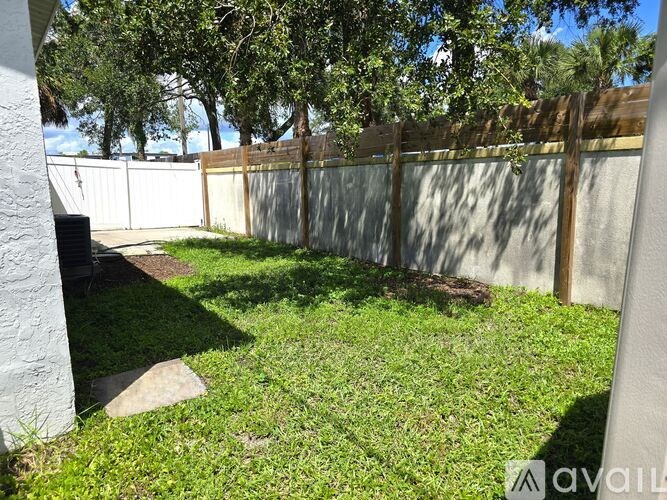 A backyard with a white fence and a tree.