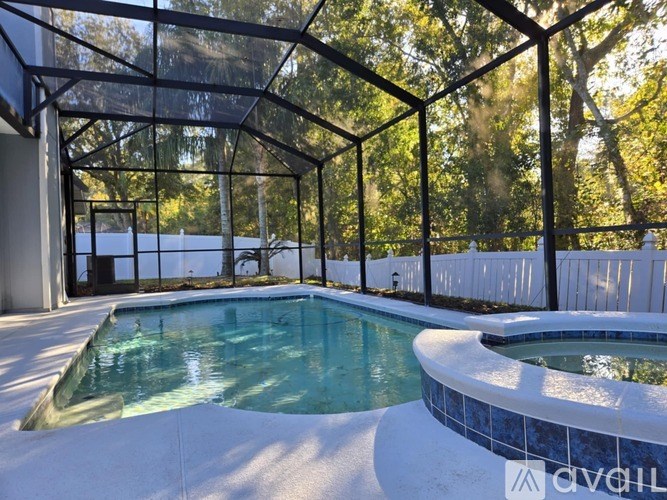 A pool enclosed by a glass wall with trees in the background.