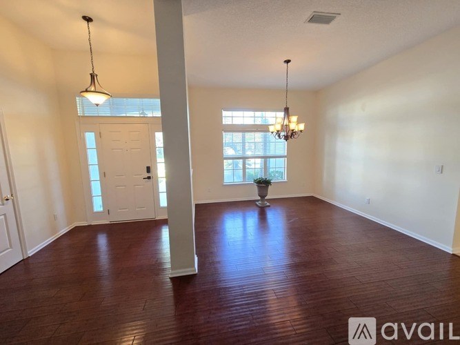 A room with wooden floors and a chandelier hanging from the ceiling.