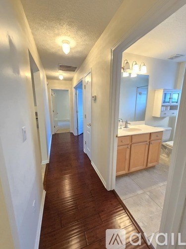 A hallway with wood flooring and white walls.