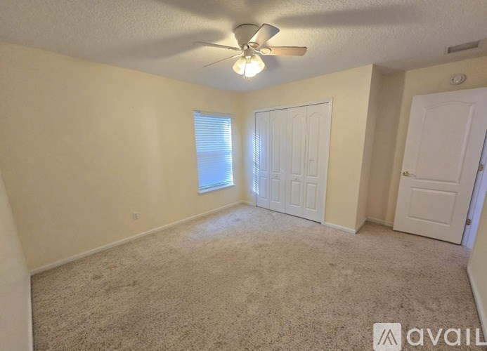 A room with a carpeted floor, a ceiling fan, and two doors.
