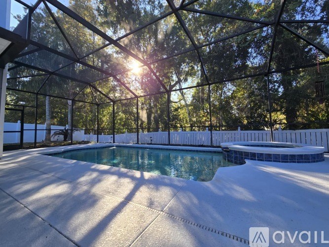 A pool enclosed by a black metal fence with trees in the background.