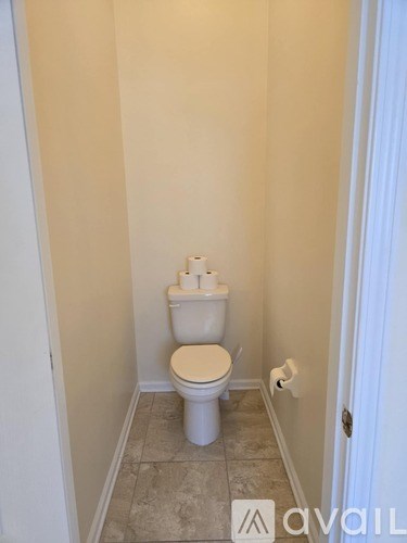 A white toilet in a small bathroom with tiled flooring and white walls.