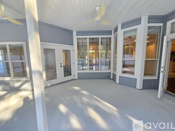 A sunny day in a spacious room with a ceiling fan and large windows.