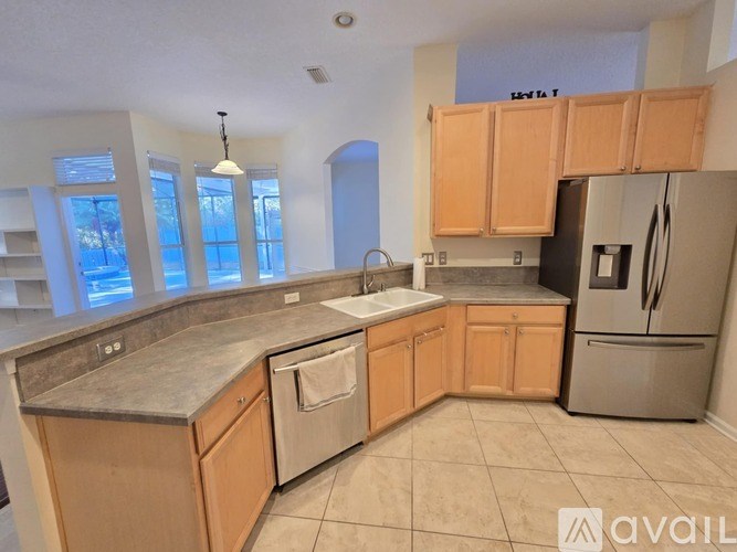 A kitchen with wooden cabinets and a stainless steel refrigerator.
