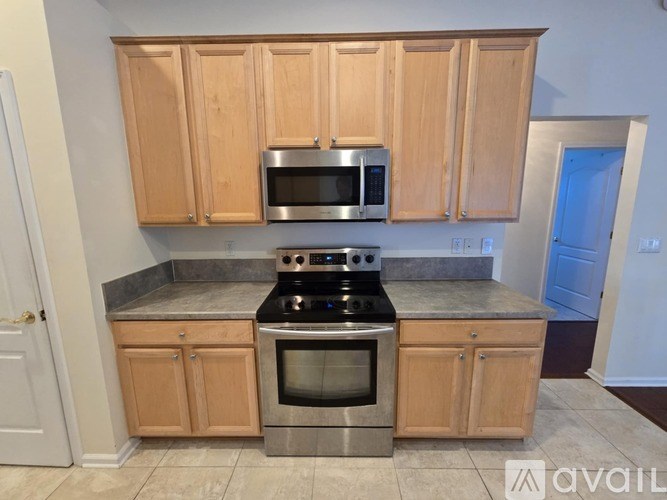 A kitchen with wooden cabinets and a stainless steel stove top oven.