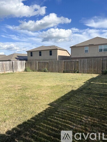 A backyard with a wooden fence and two houses in the background.