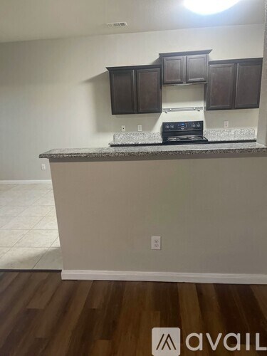 A kitchen with dark brown cabinets and a granite countertop.