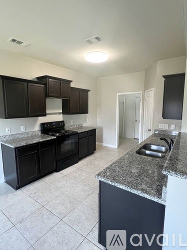A kitchen with black cabinets and granite countertops.