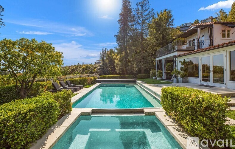 A large swimming pool surrounded by green bushes and trees.
