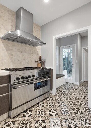 A modern kitchen with a stove top oven and a hood.