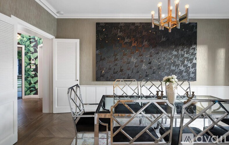 A modern dining room with a large painting on the wall and a glass table with chairs.