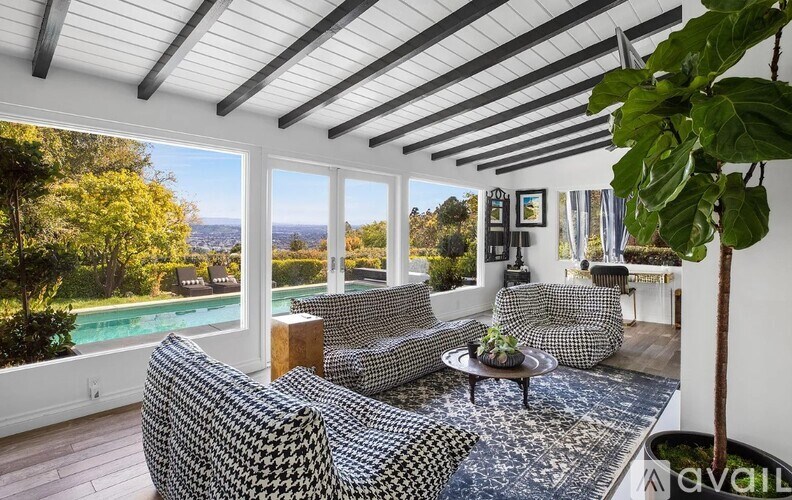 A living room with a hanging plant and a pool in the background.