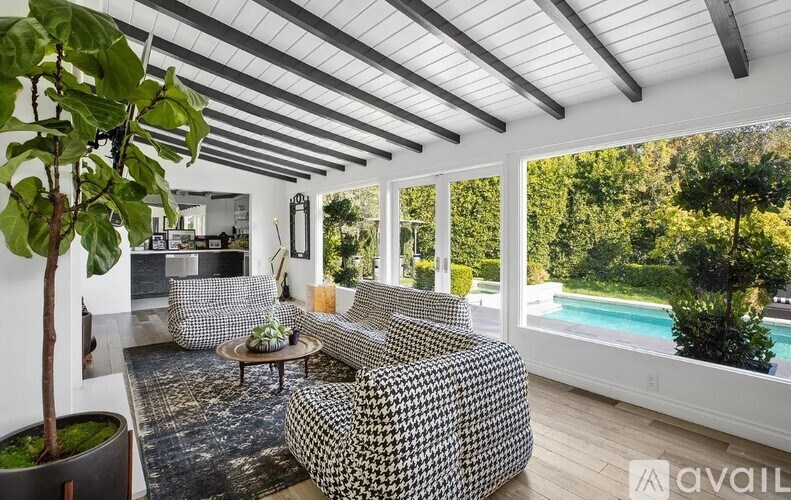 A living room with a black and white patterned sofa, a coffee table, and a large window overlooking a pool.