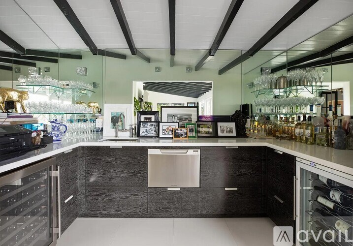 A modern bar with a black and white color scheme and a variety of glasses on the shelves.