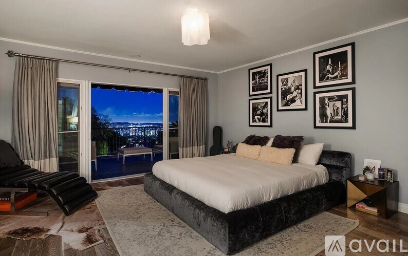 A bedroom with a large bed, a chair, and pictures on the wall.