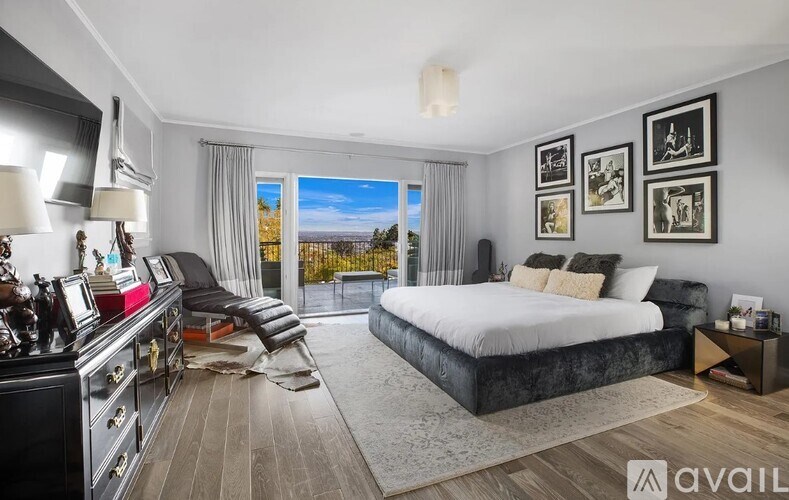 A bedroom with a large bed, a chair, and a dresser with a mirror.