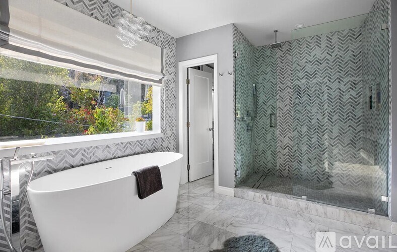 A bathroom with a white bathtub and a glass shower with a zigzag pattern.