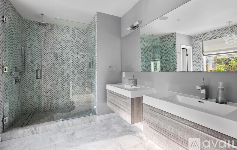 A modern bathroom with a walk-in shower and double sinks.