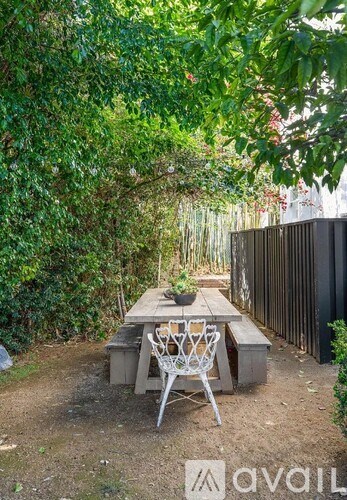 A backyard with a table and chairs surrounded by greenery.