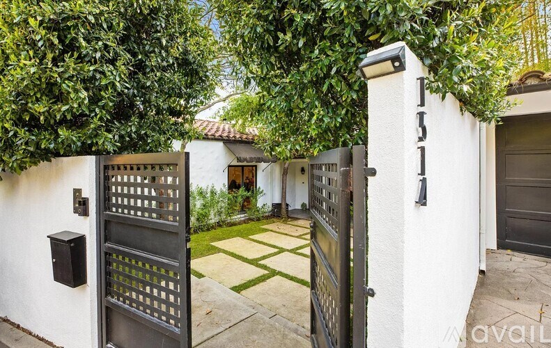 A white house with a black gate and a green tree.