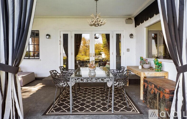 A black and white patterned rug sits in front of a glass table with a chandelier hanging from the ceiling.