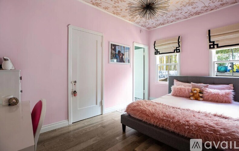 A bedroom with a bed, chair, and a window.