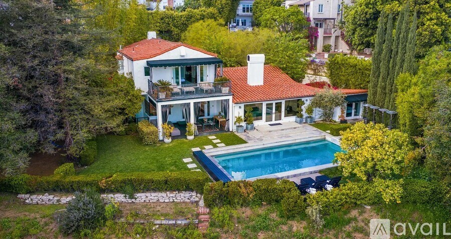 A large house with a red roof and a pool in the backyard.
