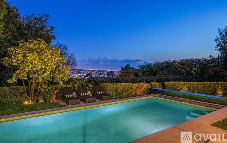 A swimming pool surrounded by greenery and trees with a cityscape in the background.