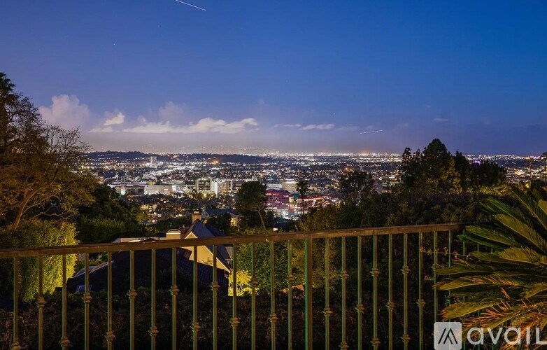 A cityscape is visible from a balcony at dusk.